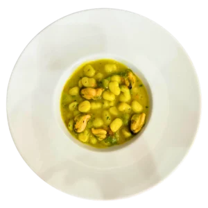 Chicche di patate con cozze, zafferano e fiori di zucca in piatto gourmet cremoso
