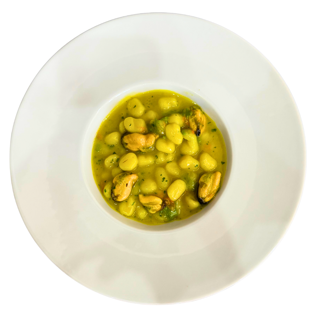 Chicche di patate con cozze, zafferano e fiori di zucca in piatto gourmet cremoso